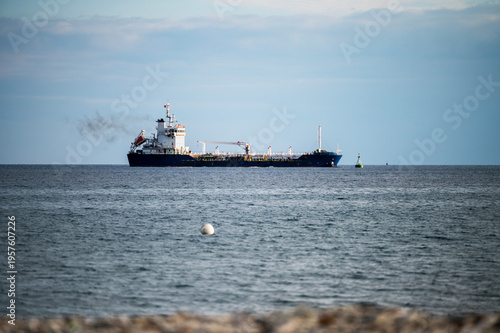 Cargo ship sailing on calm sea with buoy in the foreground