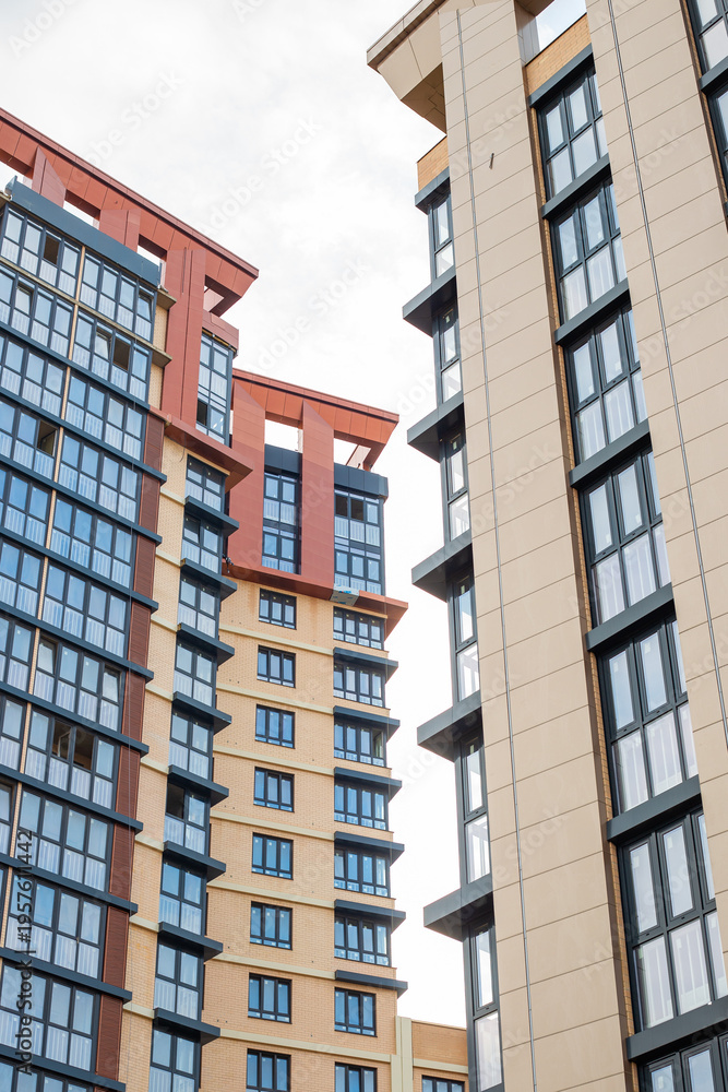 Fototapeta premium A low angle view of tall modern residential buildings against a cloudy sky. architecture, city living, apartment facade.