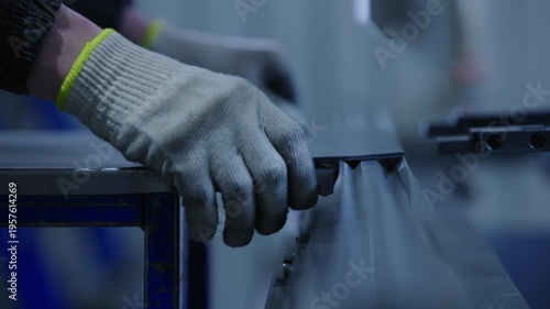 Worker cutting and feeding metal sheet on industrial assembly table in factory workshop, close moving follow.