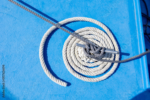 White and gray ropes coiling on blue boat deck