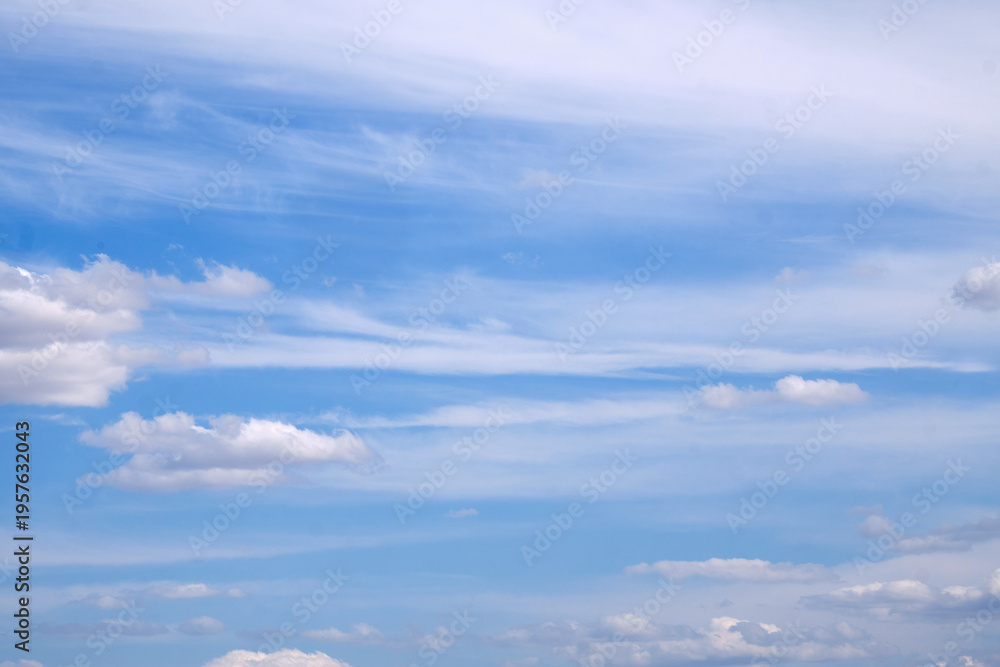 Naklejka premium Blue sky with scattered clouds, subtle blue gradients, and soft cloud formations. Space for text. Not AI.