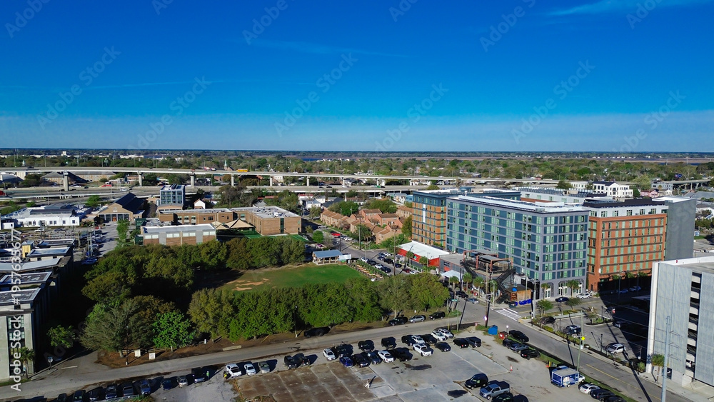 Fototapeta premium Parking areas and greenspace sit near Morrison Dr and Meeting St within Charleston Upper Peninsula corridor. Tree canopies, building facades, varied surface textures across, South Carolina