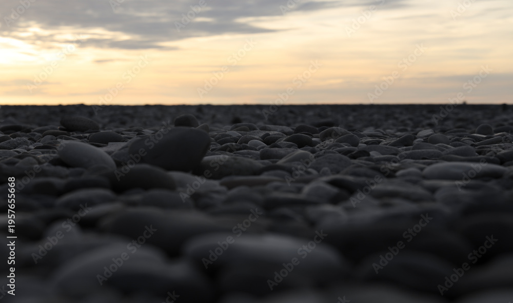 Obraz premium perspective view on washed gravel in gray, laid out on ground Grey rock gravel pebble gravel stone background Pebbles on beach in perspective Top view of round river stones floor. sunset sky Black sea