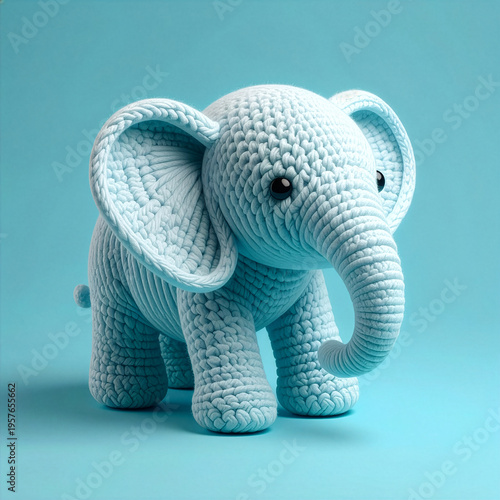A cute handmade light blue crocheted elephant toy. Adorable stuffed animal for children, isolated on a pastel blue background. Charming character with big ears and a trunk for nursery decor.