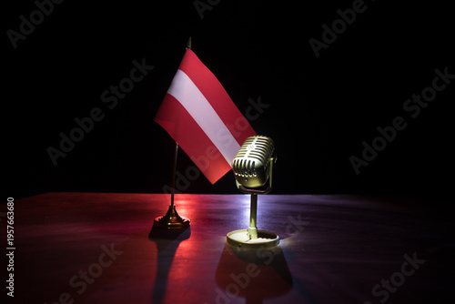 Microphone on a background of a blurry flag of Austria close-up. dark table decoration