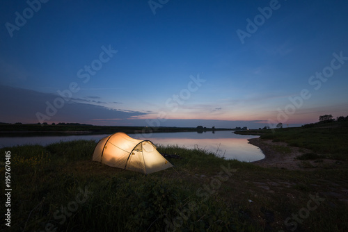 illuminated tent next to a river at night in germany
