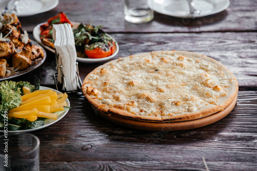 Pizza four cheeses on a wooden board in a restaurant. 