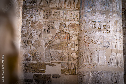 View of ancient hieroglyphs etched into weathered stone walls, telling tales of pharaohs and gods in muted ochre tones, Luxor, Luxor Governorate, Egypt.