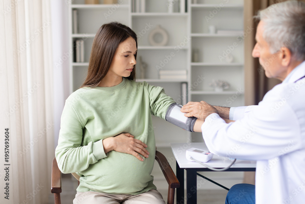 Obraz premium Doctor measuring pregnant womans blood pressure during prenatal checkup. Healthcare professional monitoring maternal health and pregnancy condition in clinic