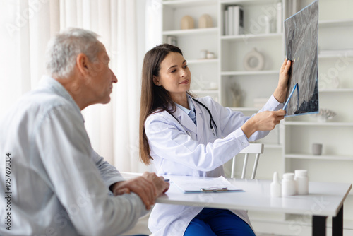 Female doctor showing medical x ray image to senior patient in clinic office. Healthcare professional explaining diagnostic results and treatment options during medical consultation
