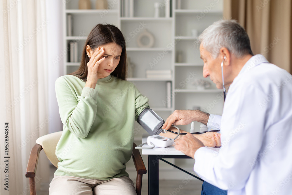Obraz premium Pregnant woman experiencing dizziness while doctor checks blood pressure during prenatal consultation. Healthcare professional assessing maternal health symptoms