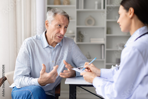Foto Senior male patient explaining symptoms to female doctor during clinic consultation