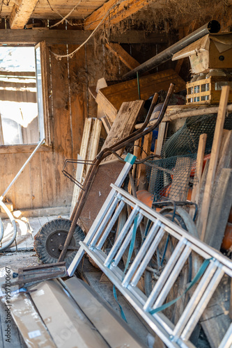 Messy old workshop interior with tools ladder and wheelbarrow, rustic workspace, concept of manual work, repair, maintenance and authentic rural lifestyle