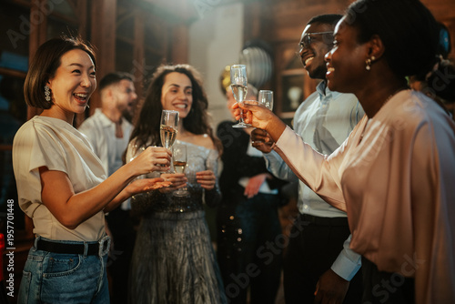 Photos Diverse group of young people cheering and smiling, making a toast with sparklin