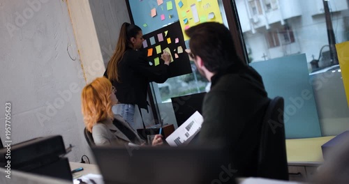 Team members collaborate on project planning using notes on wall in office space during afternoon hours with clear communication and focus on task completion