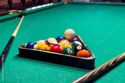 Tableau sur toile Billiard table with arranged balls, cues laid out, focus on felt texture and lig