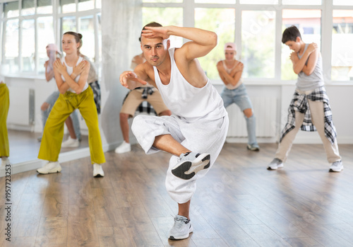 Canvastavla Young man together with group of teenage students, learn to dance hip hop in choreographic hall