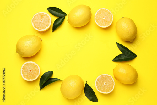 Frame of ripe lemons and leaves on yellow background, flat lay. Space for text