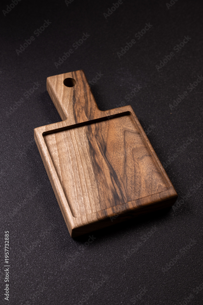 Fototapeta premium Walnut wooden serving board with handle on black background