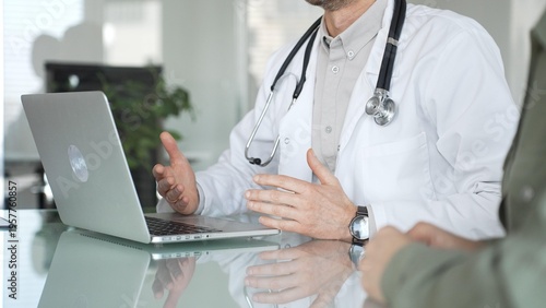 Foto Doctor man consulting patient using laptop, discussing medical information during healthcare examination in modern clinic