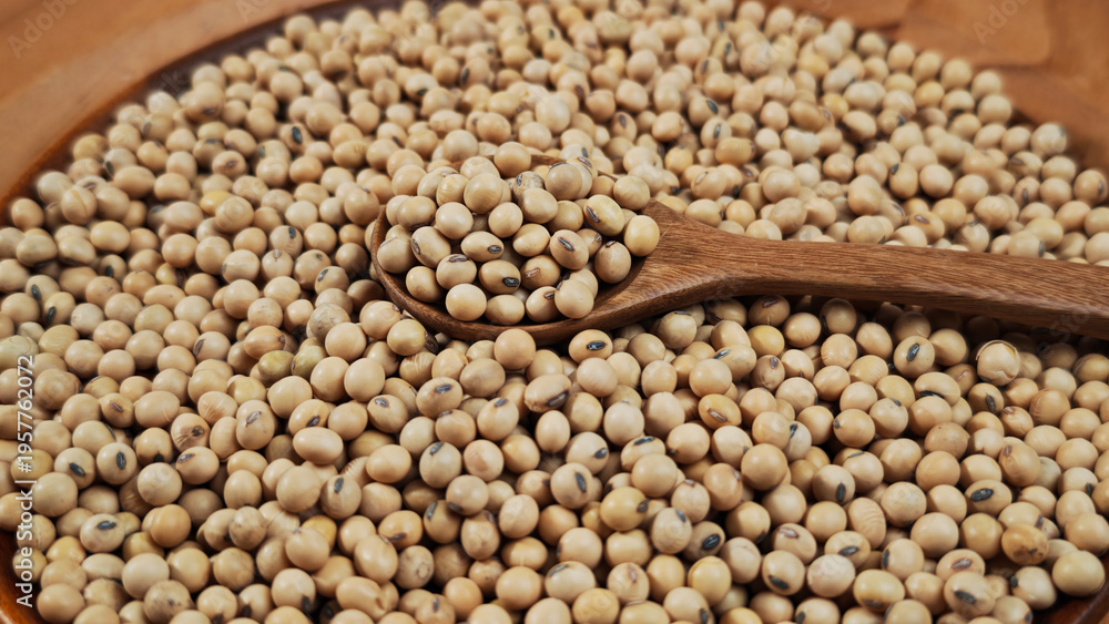Obraz premium Soybeans in a wooden spoon on plate.
