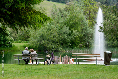 Elderly couple by the side of a lake with fountain