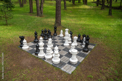Giant outdoor chess set on a board in a green park