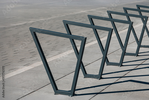 Modern metal bicycle racks casting shadows on a paved sidewalk
