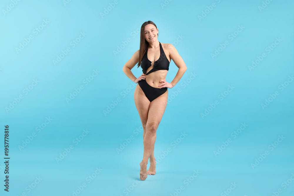 Fototapeta premium Beautiful woman wearing stylish swimsuit on light blue background