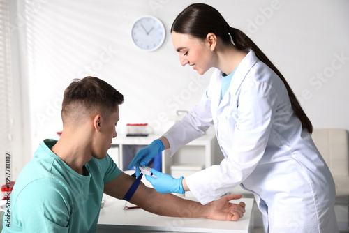 Photos Nurse putting medical tourniquet on man's arm in clinic