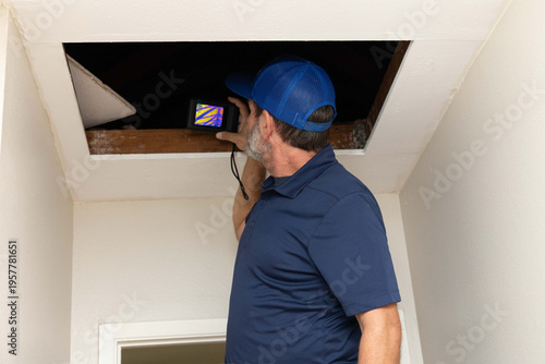 home inspector taking infrared thermography camera pictures of an attic
