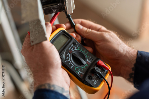 Schilderij op canvas Electrician using digital multimeter tool.