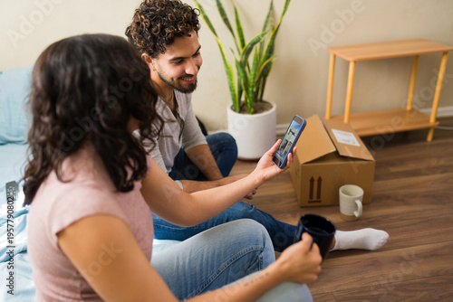Fotografie Couple living a humble life, scrolling on smartphone dreaming of a new house whi
