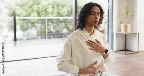 Following breathing cue, non-binary person wearing smartwatch, breathing by glass panels for calm