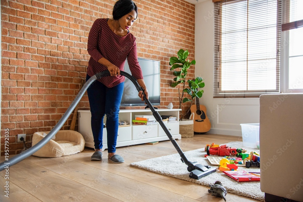 Fototapeta premium Woman vacuuming cozy living room.