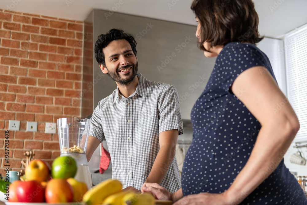 Fototapeta premium Pregnant couple enjoying kitchen conversation.