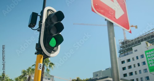 Traffic signal shifting from red to green on yellow pole, allowing vehicles to proceed, copy space
