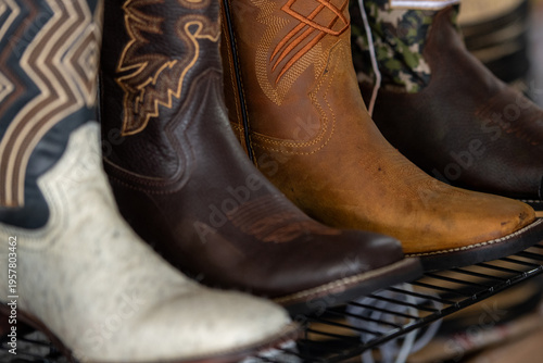 Photos A shelf with multiple new cowboy boots on display for sale at a retail store