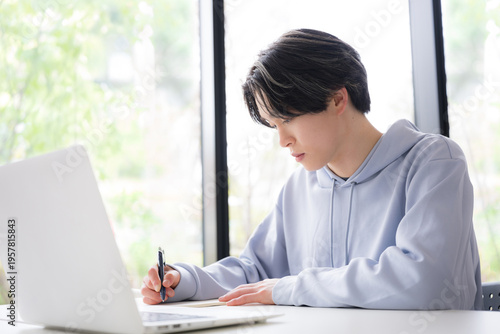 大学のキャンパスや予備校などの授業をうける大学生のような若い男性の教室や講義室で真面目に勉強する春や緑の爽やかなイメージの横顔