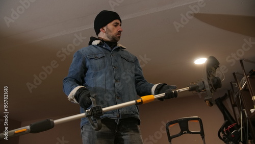 Obraz na plátne Man in warm winter clothes and gloves checking and prepping a battery powered co
