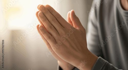 Close up of hands clasped in prayer gesture with soft lighting