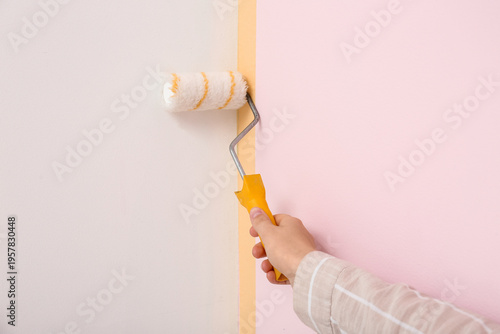 Woman painting white wall w...