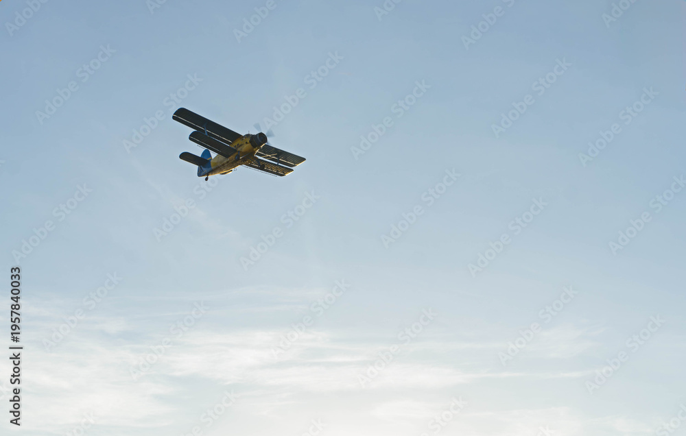 Fototapeta premium Vintage biplane flying gracefully across blue sky