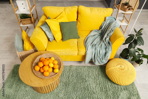 Tableau sur toile Wicker plate with citruses on coffee table near yellow sofa in stylish living ro
