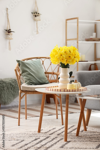 Interior of living room with armchair, coffee table and vase of narcissus flowers