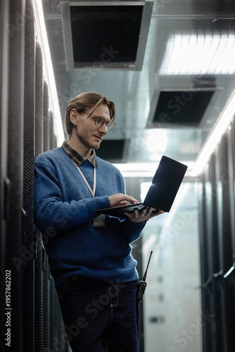 Canvastavla Caucasian middle aged man standing in server room using laptop computer, wearing