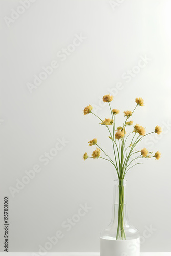 Yellow wildflower bouquet in glass vase on neutral background, delicate stems and small blossoms evoke calm and airy mood