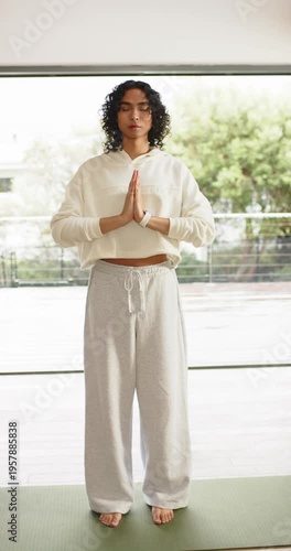 Vertical video: Non-binary person stepping onto yoga mat on balcony practicing mindfulness for calm