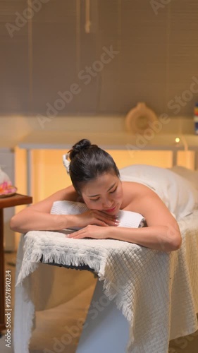 Young woman enjoying relaxing massage therapy at spa, lying on massage table.