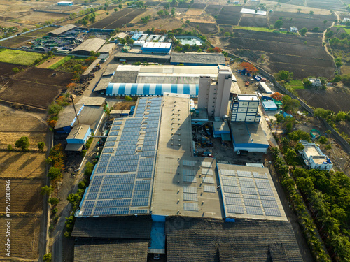 Aerial drone view of industrial factory with rooftop solar panels in rural India.